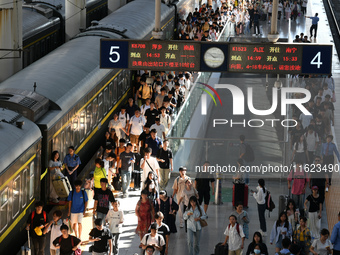 Passengers get on and off a train at Nanchang Railway Station in Nanchang, China, on September 30, 2024. (