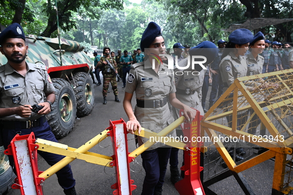 Bangladeshi police stand guard in front of the chief adviser's residence, Jamuna, as job seekers stage a demonstration on the road demanding...