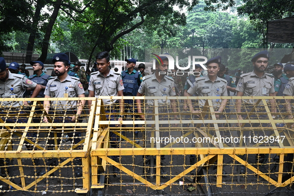 Bangladeshi police stand guard in front of the chief adviser's residence, Jamuna, as job seekers stage a demonstration on the road demanding...