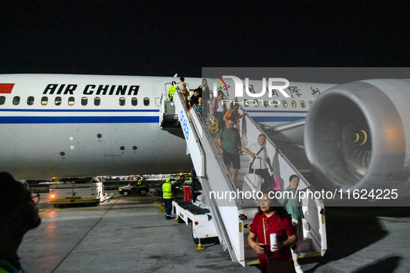 Passengers descend from a Boeing 787-9 of Air China coming from Chongqing on the tarmac of Dubai Airport in Dubai, United Arab Emirates, on...