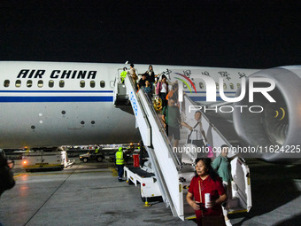 Passengers descend from a Boeing 787-9 of Air China coming from Chongqing on the tarmac of Dubai Airport in Dubai, United Arab Emirates, on...