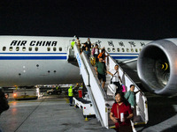 Passengers descend from a Boeing 787-9 of Air China coming from Chongqing on the tarmac of Dubai Airport in Dubai, United Arab Emirates, on...