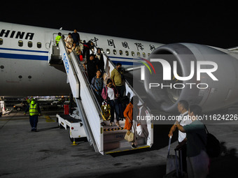 Passengers descend from a Boeing 787-9 of Air China coming from Chongqing on the tarmac of Dubai Airport in Dubai, United Arab Emirates, on...