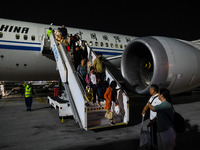 Passengers descend from a Boeing 787-9 of Air China coming from Chongqing on the tarmac of Dubai Airport in Dubai, United Arab Emirates, on...