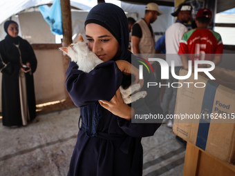 A Palestinian girl carries her cat at a newly opened clinic for animal care at a displacement camp in Deir el-Balah in the central Gaza Stri...