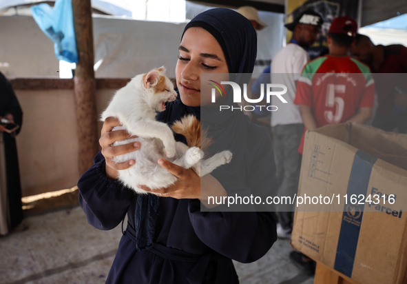 A Palestinian girl carries her cat at a newly opened clinic for animal care at a displacement camp in Deir el-Balah in the central Gaza Stri...