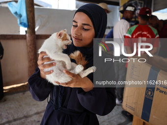 A Palestinian girl carries her cat at a newly opened clinic for animal care at a displacement camp in Deir el-Balah in the central Gaza Stri...