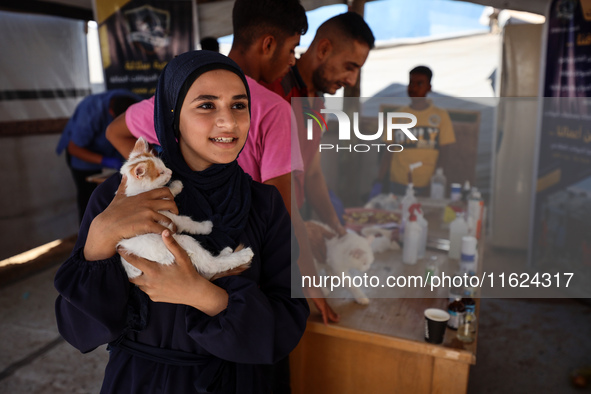 A Palestinian girl carries her cat at a newly opened clinic for animal care at a displacement camp in Deir el-Balah in the central Gaza Stri...