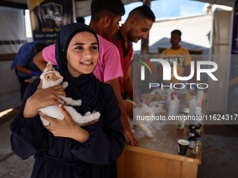 A Palestinian girl carries her cat at a newly opened clinic for animal care at a displacement camp in Deir el-Balah in the central Gaza Stri...