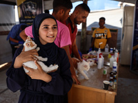 A Palestinian girl carries her cat at a newly opened clinic for animal care at a displacement camp in Deir el-Balah in the central Gaza Stri...