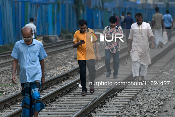 Pedestrians walk along a railway line while using their mobile phones in Dhaka, Bangladesh, on September 30, 2024. In Bangladesh, a signific...