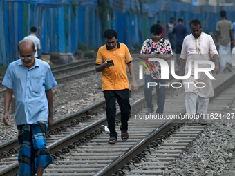 Pedestrians walk along a railway line while using their mobile phones in Dhaka, Bangladesh, on September 30, 2024. In Bangladesh, a signific...