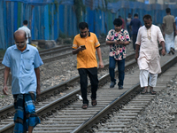 Pedestrians walk along a railway line while using their mobile phones in Dhaka, Bangladesh, on September 30, 2024. In Bangladesh, a signific...