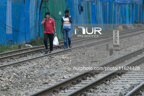 Pedestrians walk along a railway line while using their mobile phones in Dhaka, Bangladesh, on September 30, 2024. In Bangladesh, a signific...