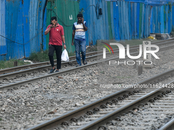 Pedestrians walk along a railway line while using their mobile phones in Dhaka, Bangladesh, on September 30, 2024. In Bangladesh, a signific...