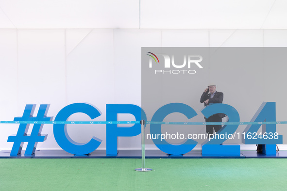 A man on the phone stands behind a giant #CPC24 at the Conservative Party Conference at the International Conference Centre in Birmingham, E...