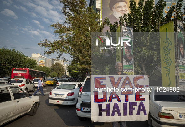 An elderly Iranian protester holds an anti-Israeli placard while taking part in a protest gathering to condemn an Israeli air strike against...