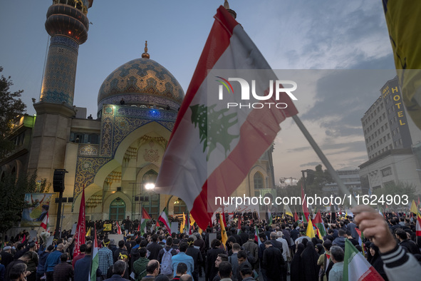 An Iranian protester waves a Lebanese flag while taking part in a protest gathering to condemn an Israeli air strike against Hezbollah's hea...