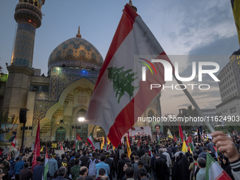 An Iranian protester waves a Lebanese flag while taking part in a protest gathering to condemn an Israeli air strike against Hezbollah's hea...