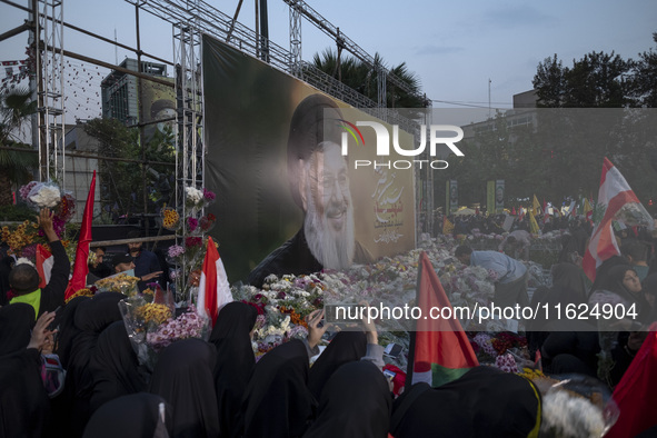 Iranian protesters place flowers under a giant banner featuring a portrait of Lebanon's Hezbollah Secretary General, Hassan Nasrallah, while...