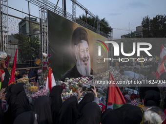 Iranian protesters place flowers under a giant banner featuring a portrait of Lebanon's Hezbollah Secretary General, Hassan Nasrallah, while...