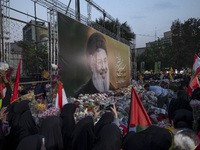 Iranian protesters place flowers under a giant banner featuring a portrait of Lebanon's Hezbollah Secretary General, Hassan Nasrallah, while...