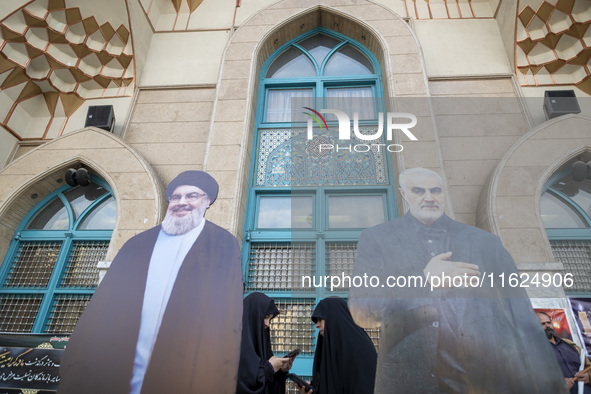 Two veiled Iranian women stand together behind effigies of Lebanon's Hezbollah Secretary General, Hassan Nasrallah, and former commander of...