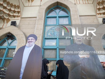 Two veiled Iranian women stand together behind effigies of Lebanon's Hezbollah Secretary General, Hassan Nasrallah, and former commander of...