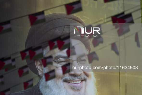 Palestinian flags hang in front of a portrait of Lebanon's Hezbollah Secretary General, Hassan Nasrallah, during a protest gathering to cond...