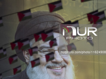 Palestinian flags hang in front of a portrait of Lebanon's Hezbollah Secretary General, Hassan Nasrallah, during a protest gathering to cond...