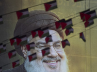 Palestinian flags hang in front of a portrait of Lebanon's Hezbollah Secretary General, Hassan Nasrallah, during a protest gathering to cond...