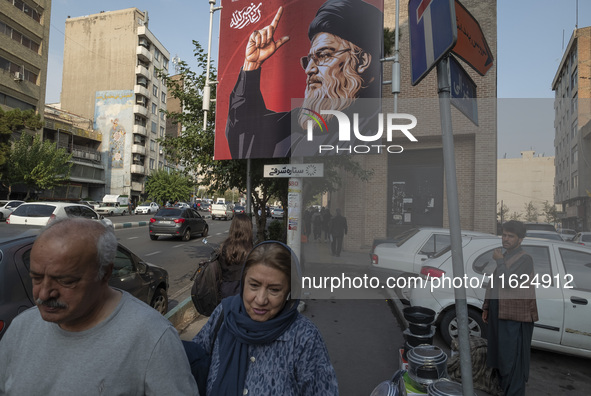 Iranian people walk under a billboard featuring a portrait of Lebanon's Hezbollah Secretary General, Hassan Nasrallah, who was killed in an...