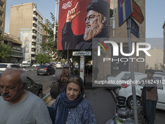 Iranian people walk under a billboard featuring a portrait of Lebanon's Hezbollah Secretary General, Hassan Nasrallah, who was killed in an...