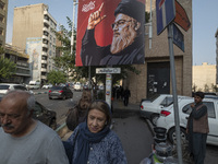 Iranian people walk under a billboard featuring a portrait of Lebanon's Hezbollah Secretary General, Hassan Nasrallah, who was killed in an...