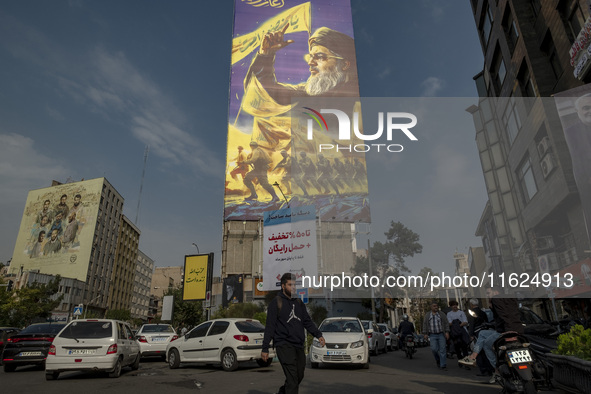 A young Iranian man walks under a giant banner featuring a portrait of Lebanon's Hezbollah Secretary General, Hassan Nasrallah, in Tehran, I...