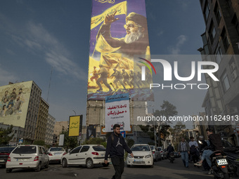 A young Iranian man walks under a giant banner featuring a portrait of Lebanon's Hezbollah Secretary General, Hassan Nasrallah, in Tehran, I...