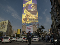 A young Iranian man walks under a giant banner featuring a portrait of Lebanon's Hezbollah Secretary General, Hassan Nasrallah, in Tehran, I...