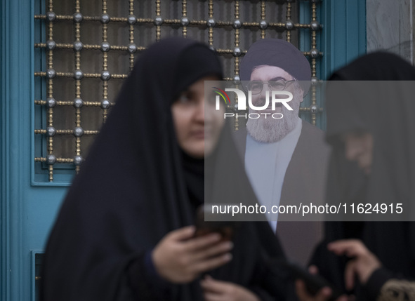 Two veiled Iranian women stand together in front of an effigy of Lebanon's Hezbollah Secretary General, Hassan Nasrallah, while taking part...