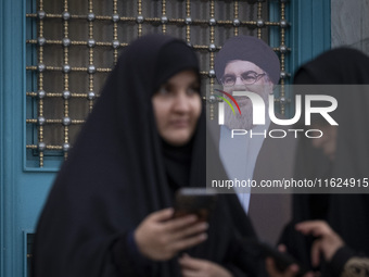 Two veiled Iranian women stand together in front of an effigy of Lebanon's Hezbollah Secretary General, Hassan Nasrallah, while taking part...