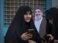 Two veiled Iranian women stand together in front of an effigy of Lebanon's Hezbollah Secretary General, Hassan Nasrallah, while taking part...