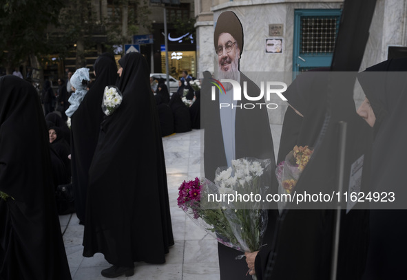 Veiled Iranian protesters hold flowers while standing next to an effigy of Lebanon's Hezbollah Secretary General, Hassan Nasrallah, during a...