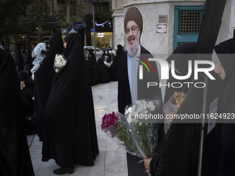 Veiled Iranian protesters hold flowers while standing next to an effigy of Lebanon's Hezbollah Secretary General, Hassan Nasrallah, during a...