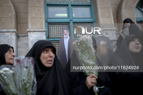 Veiled Iranian protesters hold flowers while sitting in front of effigies of Lebanon's Hezbollah Secretary General, Hassan Nasrallah, and fo...