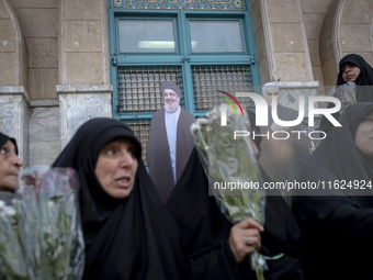 Veiled Iranian protesters hold flowers while sitting in front of effigies of Lebanon's Hezbollah Secretary General, Hassan Nasrallah, and fo...