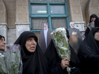 Veiled Iranian protesters hold flowers while sitting in front of effigies of Lebanon's Hezbollah Secretary General, Hassan Nasrallah, and fo...