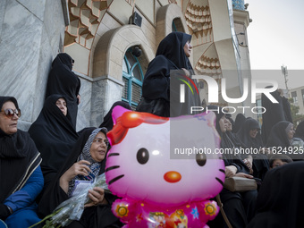 Veiled Iranian protesters stand behind a Hello Kitty-shaped balloon while taking part in a protest gathering to condemn an Israeli air strik...