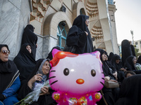 Veiled Iranian protesters stand behind a Hello Kitty-shaped balloon while taking part in a protest gathering to condemn an Israeli air strik...