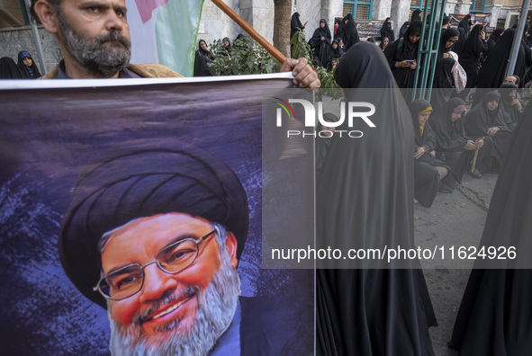 An Iranian protester holds a banner featuring a portrait of Lebanon's Hezbollah Secretary General, Hassan Nasrallah, while taking part in a...