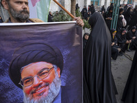 An Iranian protester holds a banner featuring a portrait of Lebanon's Hezbollah Secretary General, Hassan Nasrallah, while taking part in a...