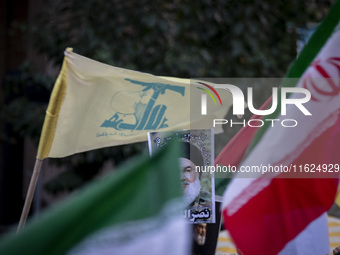 Iranian protesters wave a Lebanon's Hezbollah flag and an Iranian flag next to a portrait of Hezbollah Secretary General, Hassan Nasrallah,...